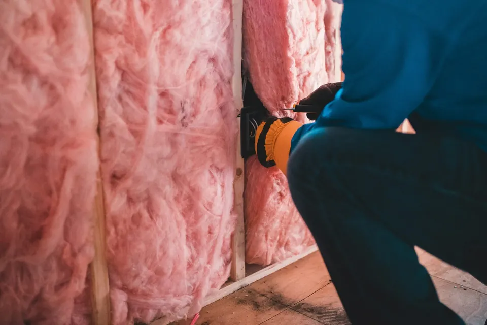 Artisan posant un isolant dans une ossature