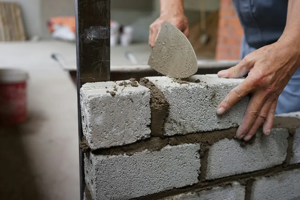 Maçon réalisant un mur en blocs et mortier
